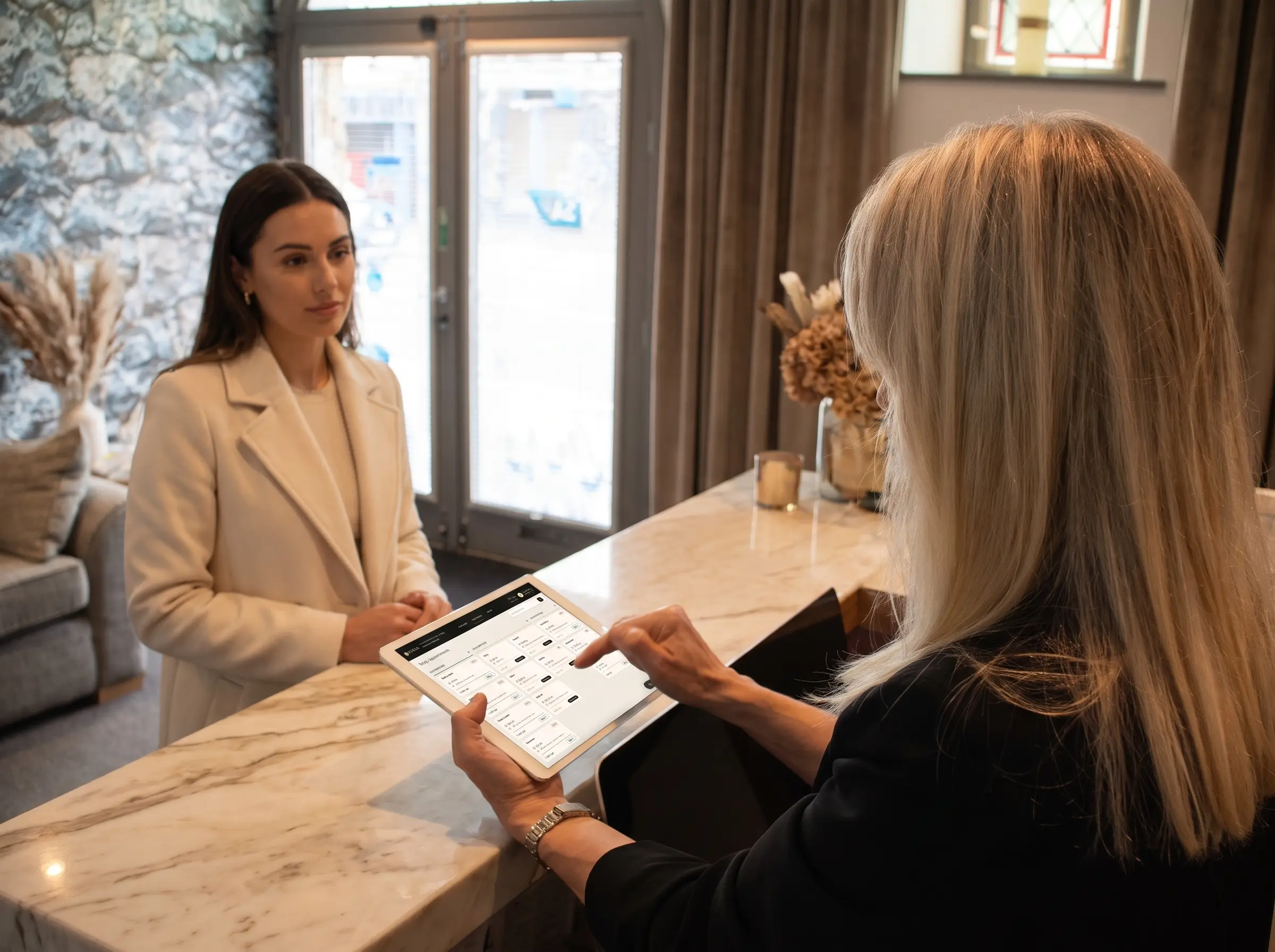 A client at a marble front desk while the book is opened on a tablet
